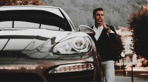 man with cigar beside porsche car